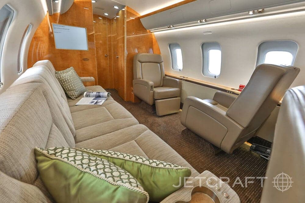 Interior of the aircraft with a sofa, recliner, and wood paneling.