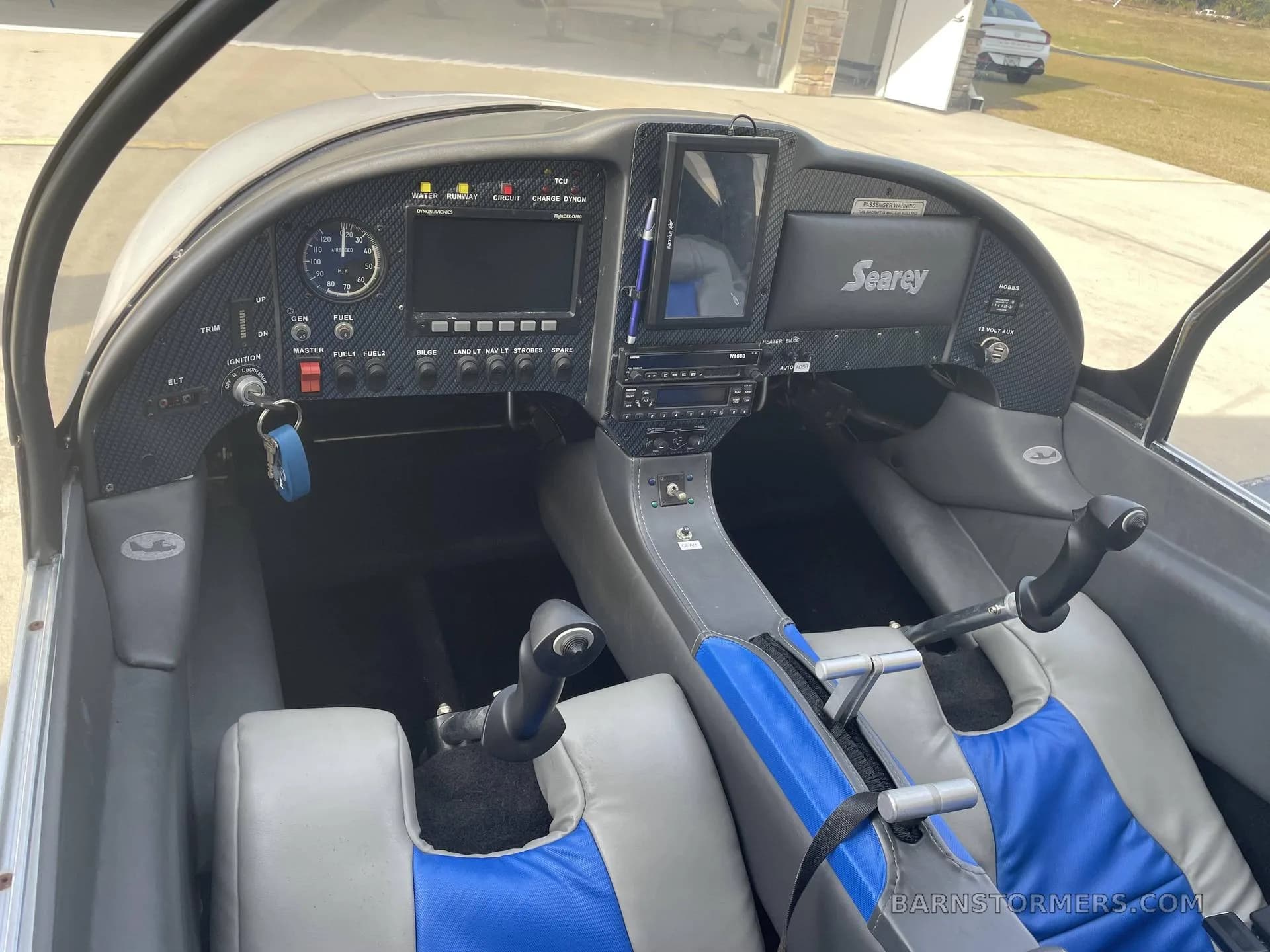 The cockpit of a Searey aircraft, showing the instrument panel, controls, and blue and grey seats.