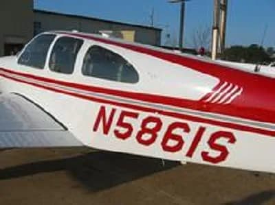 Close-up view of the white fuselage with red stripes and registration N5861S of a Beechcraft Bonanza.