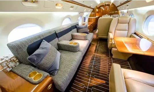 Interior of a private jet with a sofa and leather seats.