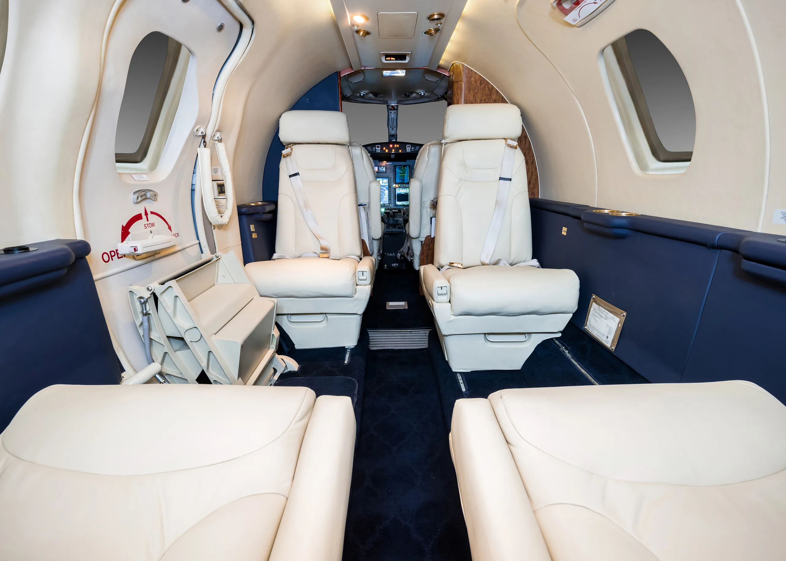 Interior view of the aircraft cabin with white leather seats and blue accents.