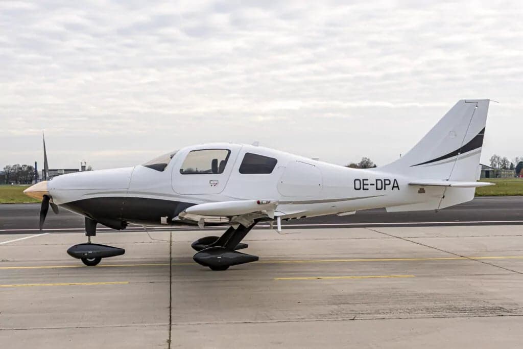 A white and black aircraft with the registration OE-DPA parked on the tarmac.