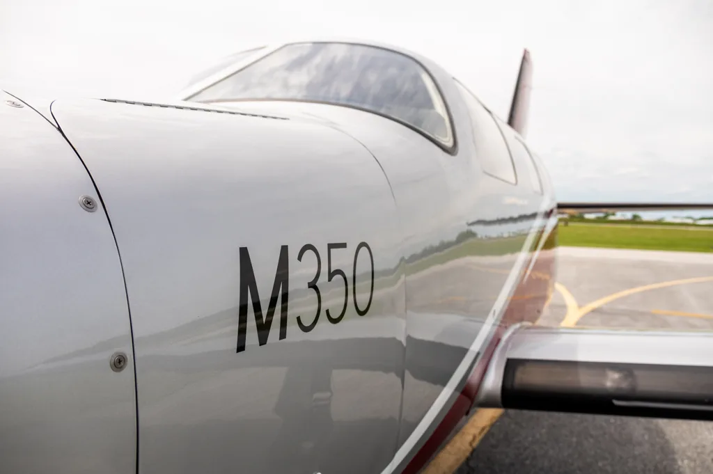 A close-up view of the white fuselage of a Piper M350 aircraft, showing the model designation.