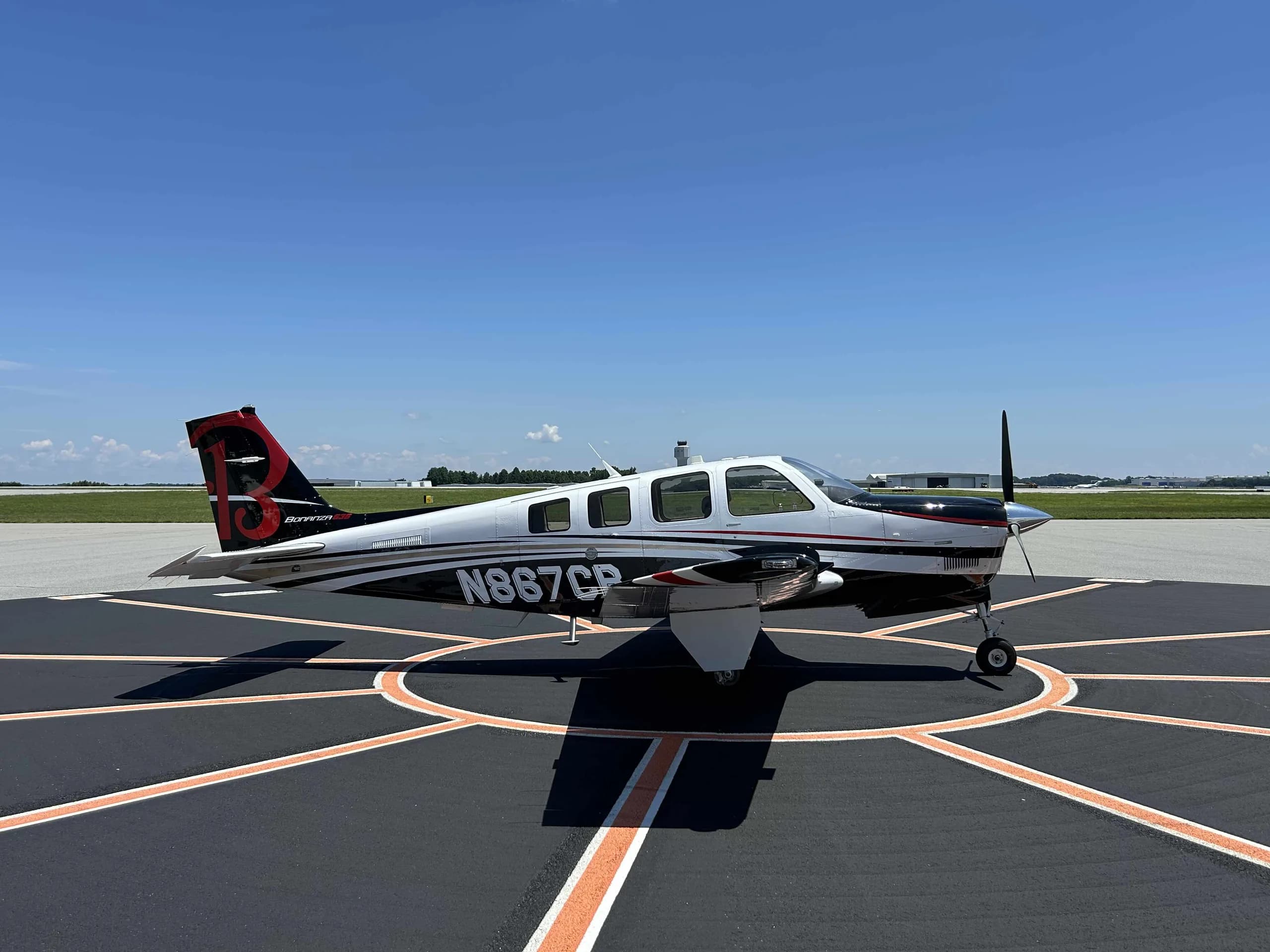 Beechcraft Bonanza with white and black paint scheme on a tarmac.