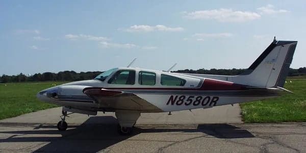 Side view of a white and maroon aircraft with tail number N8580R on a paved surface.