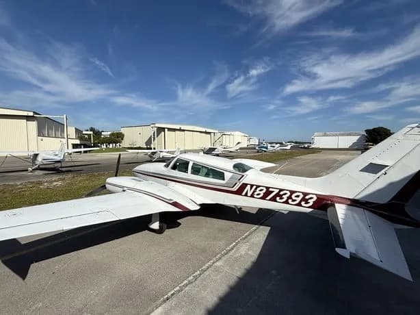 Rear-side view of a white twin-engine aircraft with N87393 on the tail, parked on an airfield.
