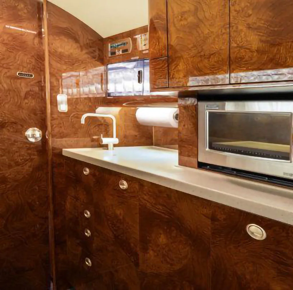 The aircraft's galley area featuring a sink, microwave, and rich wood cabinetry.