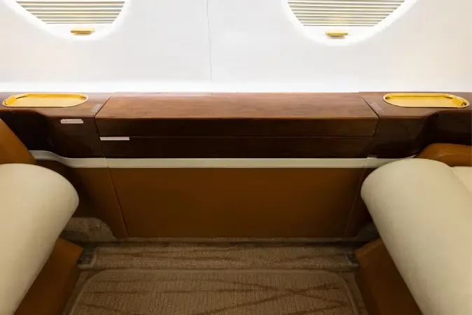 A detailed view of the aircraft cabin's dark wood side paneling, cream seat bases, and window blinds.