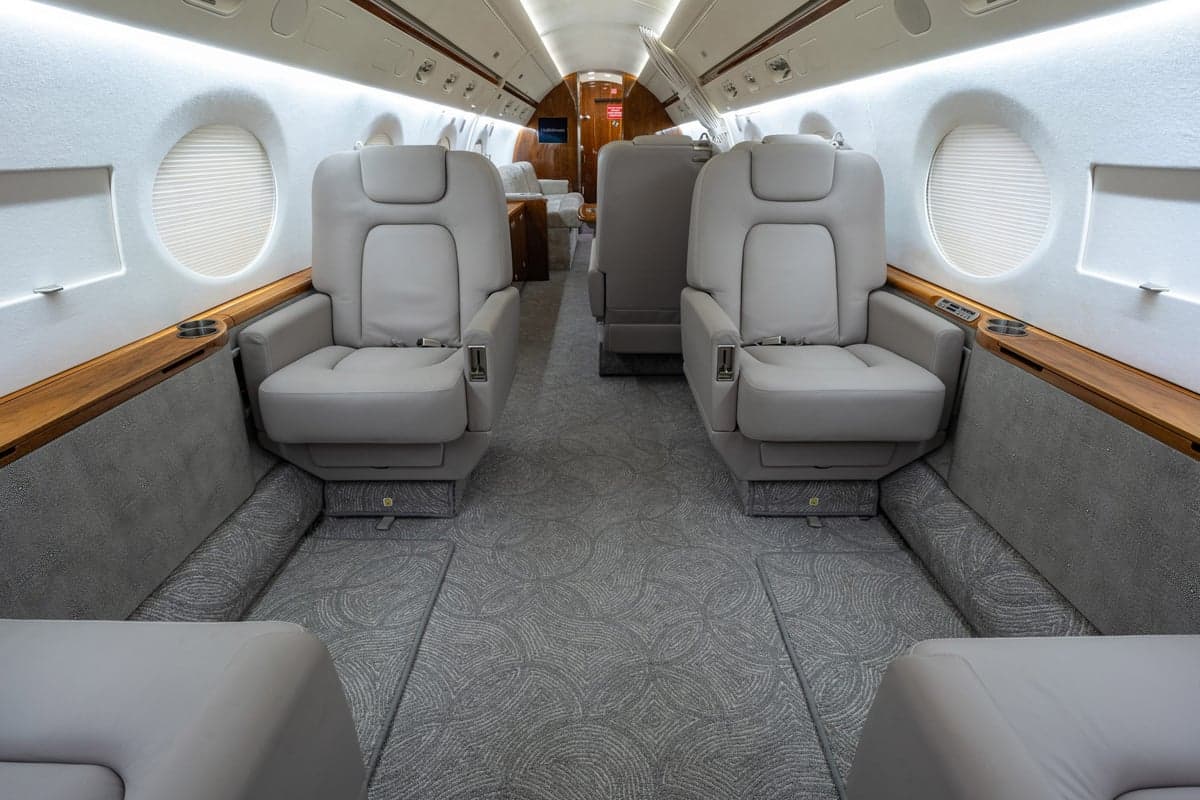 The aircraft's interior features comfortable seating and wood trim.