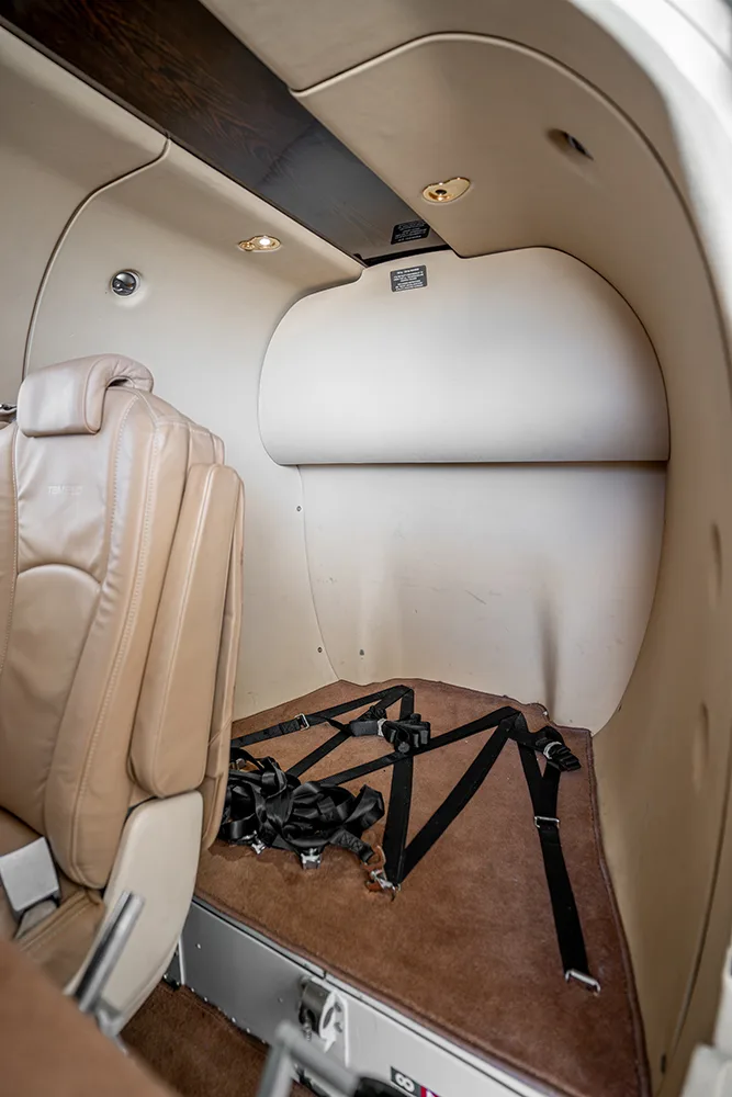 A view of the aircraft's rear cabin area with a single seat and cargo straps on the floor.