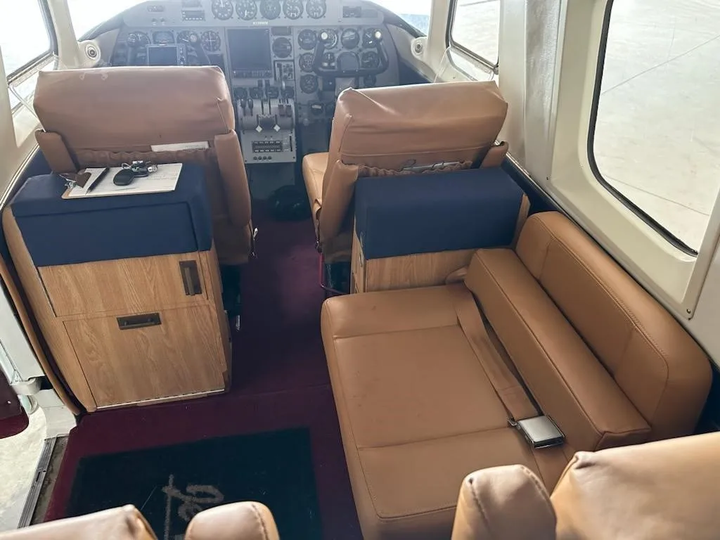The aircraft's cabin interior with tan leather seats and the cockpit visible in the background.