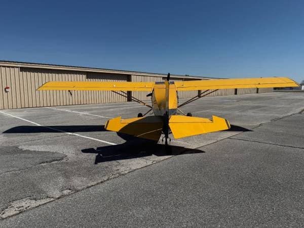 Rear view of a yellow and blue Maule M-7-235 aircraft parked on the tarmac.