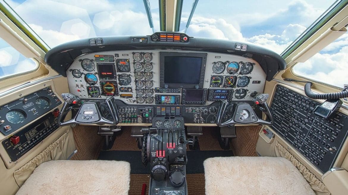 Aircraft cockpit with instrument panel and sheepskin seat covers.