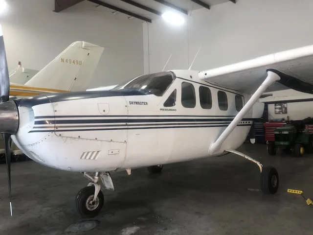 Side view of a blue and white Cessna Skymaster in a hangar.