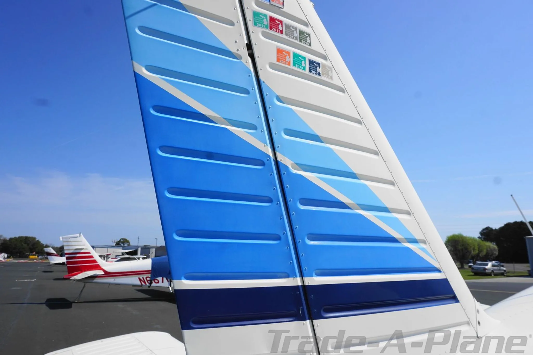 Close-up of the aircraft's vertical stabilizer showing blue and white stripes and inspection stickers.