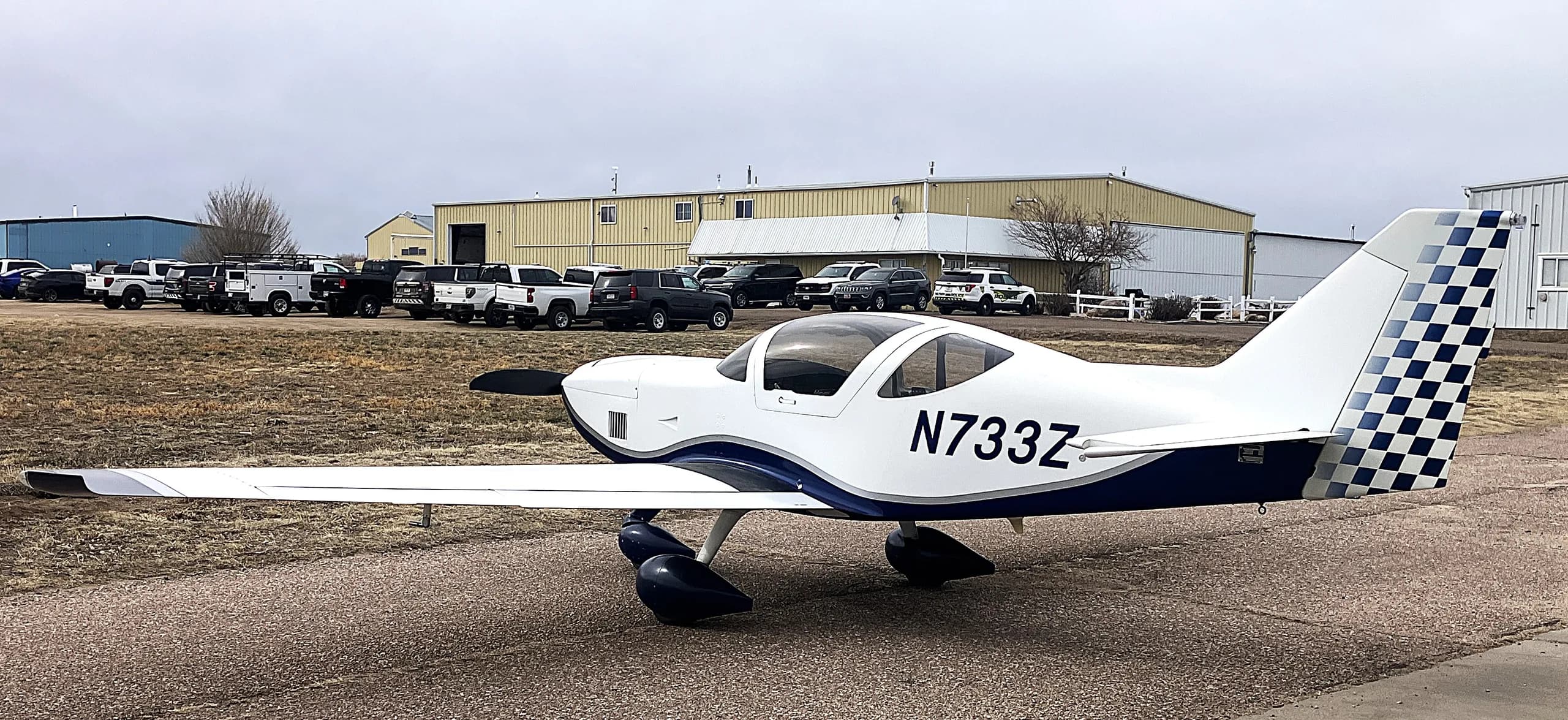 A white and blue Glasair Sportsman aircraft (N733Z) parked on an airfield, viewed from the rear-right side.