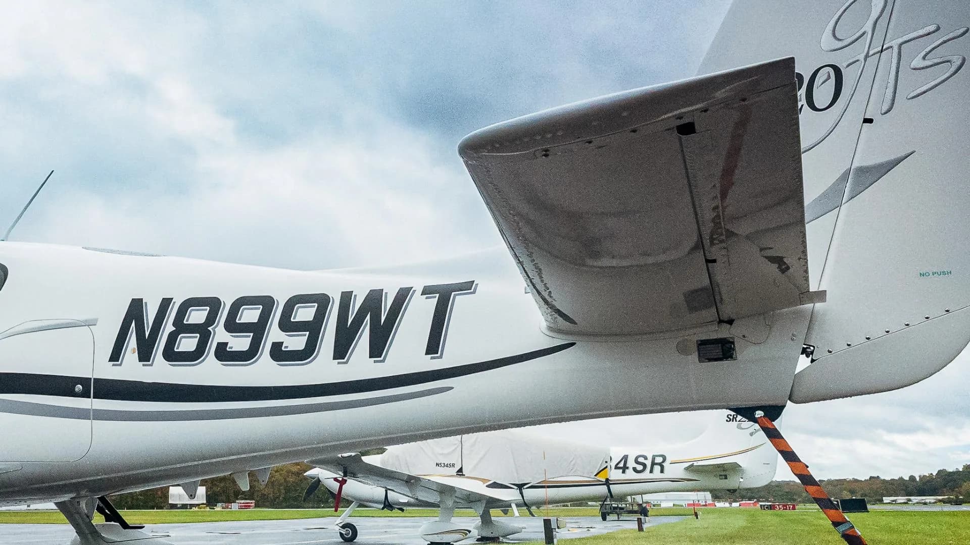 A close-up view of the tail and fuselage of a white Cirrus SR20 aircraft, showing registration N899WT and the SR20 Gts logo.