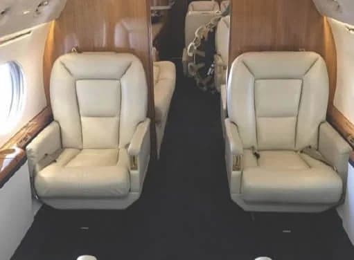 Close-up of two cream-colored leather seats in the aircraft cabin.