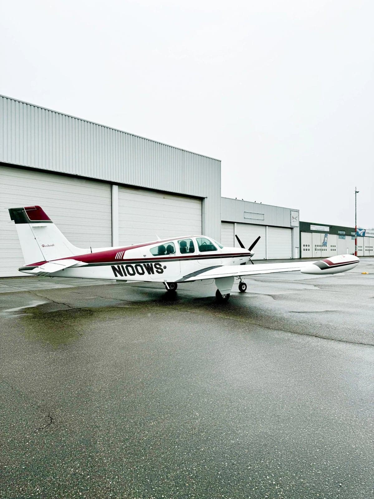 N100WS Bonanza aircraft parked in front of a hangar.
