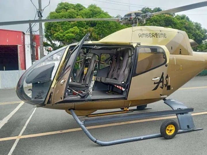 Front side view of a gold helicopter with the door open, showing the interior.