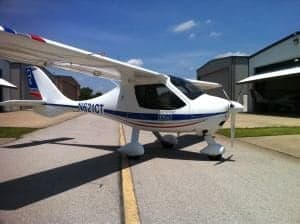 A white and blue light sport aircraft with registration N621CT parked on the tarmac.