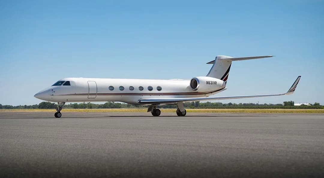 A white Gulfstream G550 business jet with red and black tail stripes, registration N631VR, parked on an airfield.