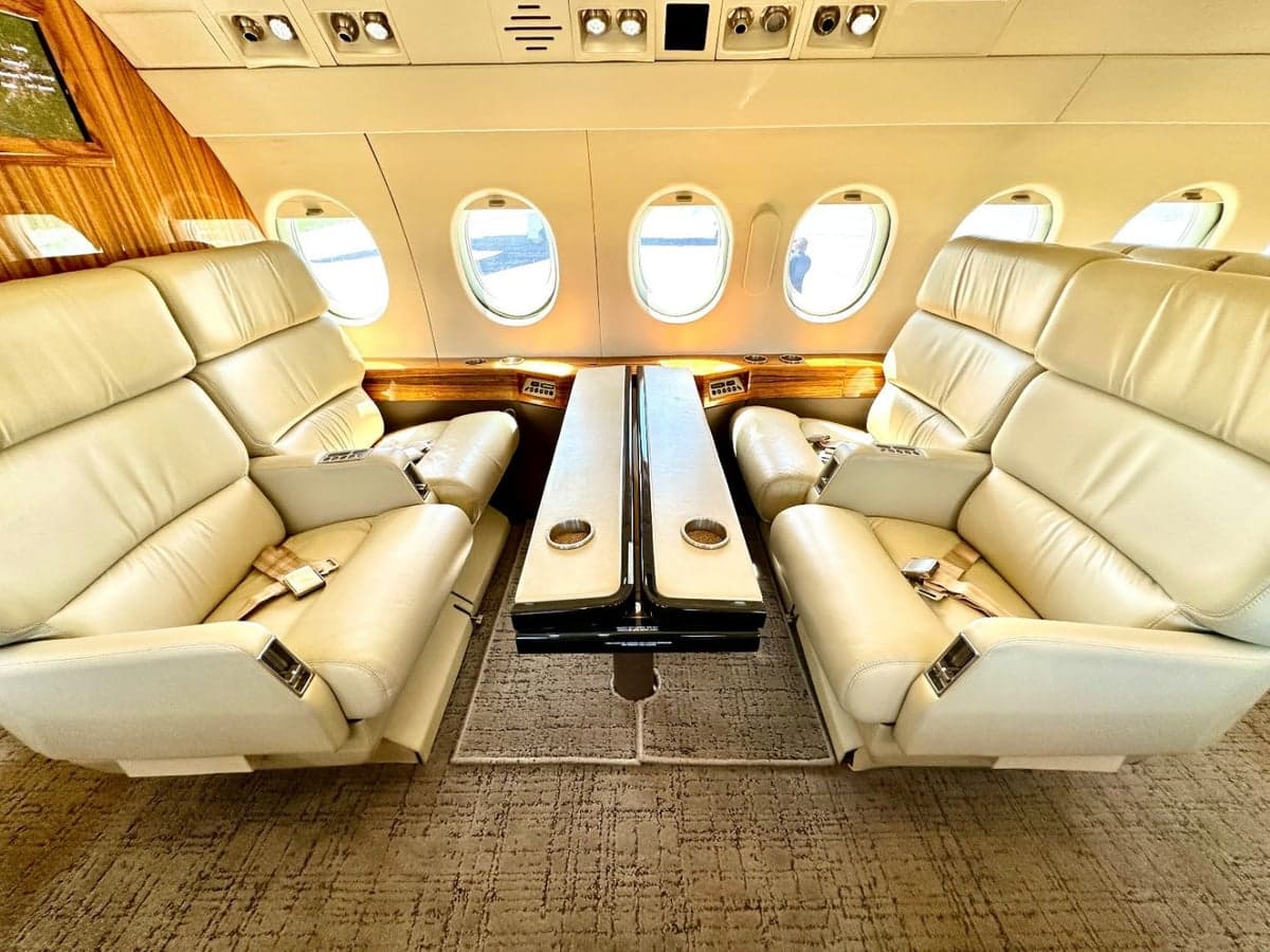 View of the aircraft's interior with cream-colored leather seats and a wooden table.