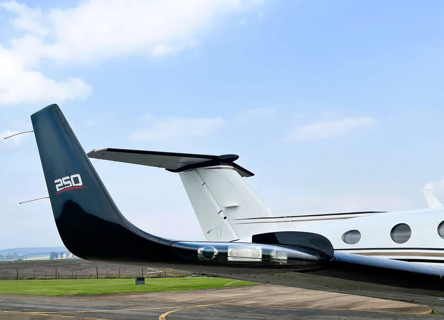 A close-up view of the black tail and wingtip of a Beechcraft King Air 250 aircraft on the tarmac.