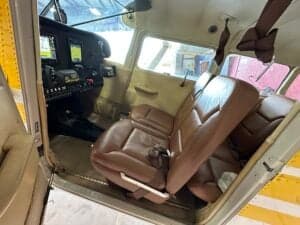 The interior of a Cessna 185 Skywagon features brown leather seats and a view of the cockpit.