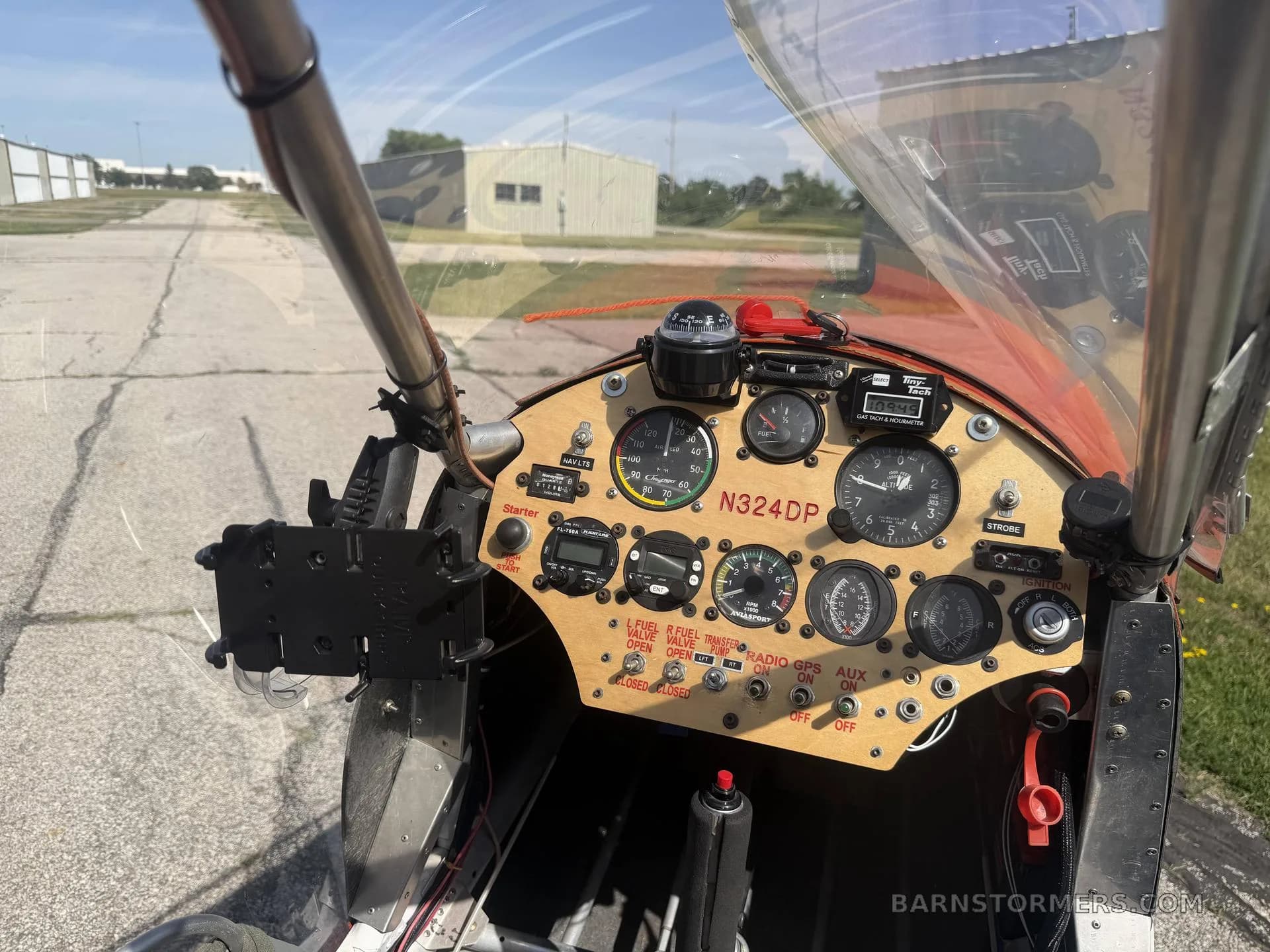 A view from the cockpit of a light aircraft, showing the wooden instrument panel with various gauges and controls, and the runway ahead.