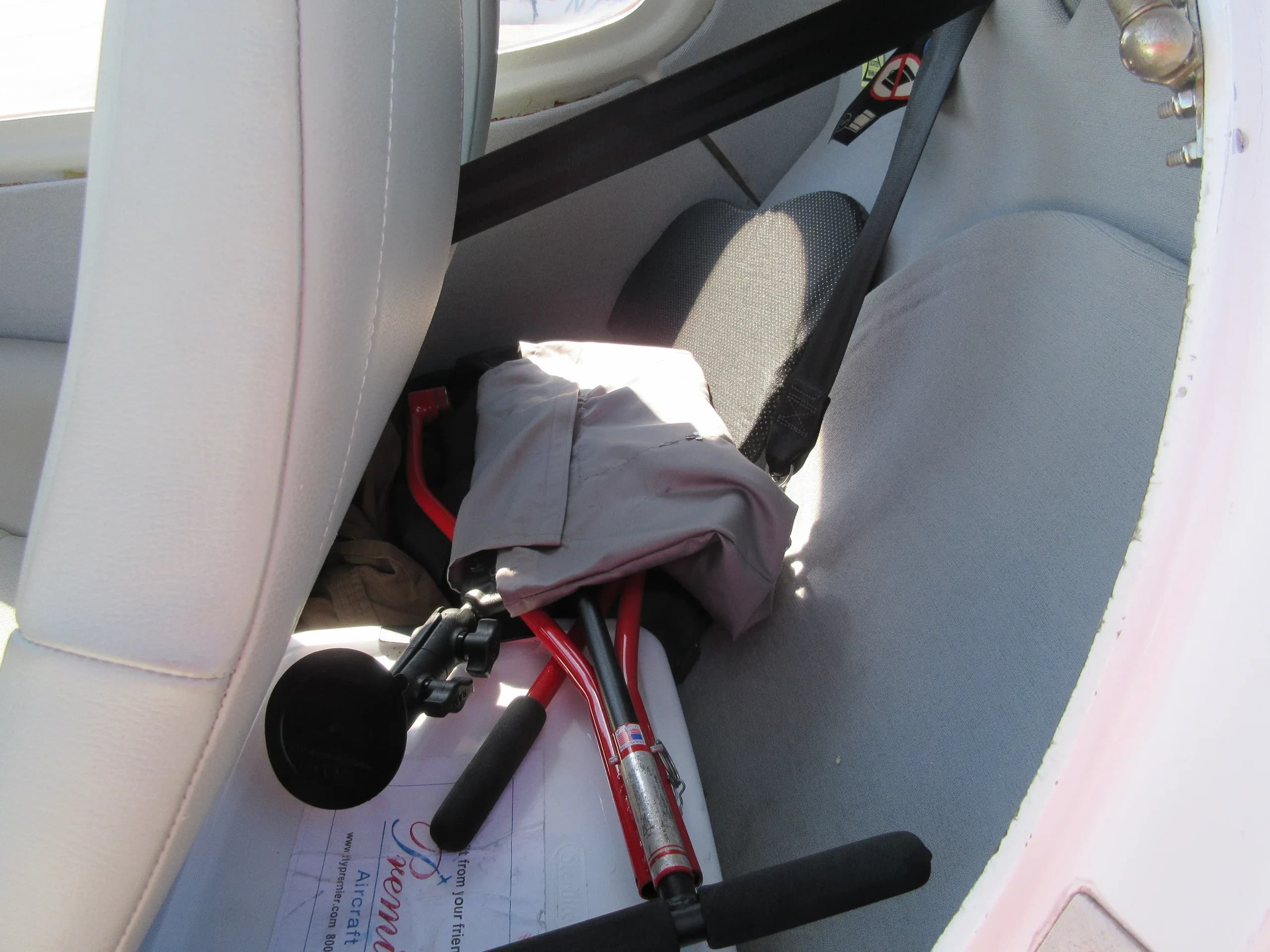 The interior of a Diamond aircraft showing the area behind the front seats with a red tow bar and other equipment.