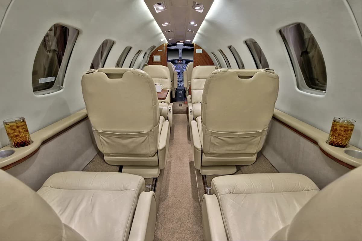 Aircraft interior with tan leather seats and a view towards the cockpit.