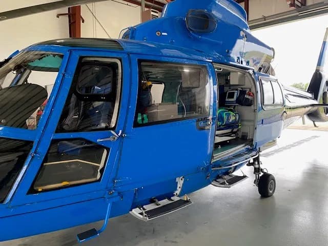 Close-up of the blue and black Airbus AS365 N3 Dauphin helicopter with the door open.