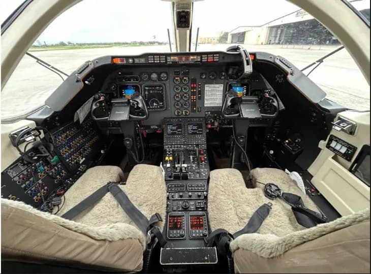 Aircraft cockpit with instrument panel and sheepskin seat covers.