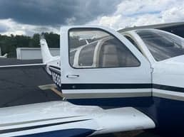 Side view of a Beechcraft Bonanza with the door open, showing the registration number N838EB.