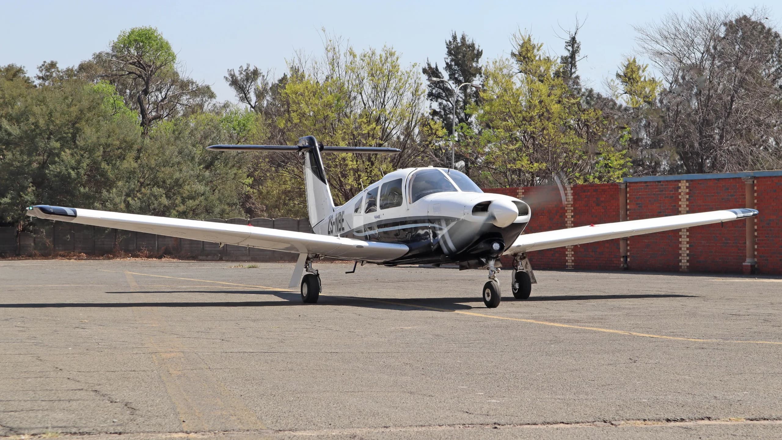A white and black Piper PA-28-201T Turbo Arrow IV aircraft parked on an asphalt ramp.