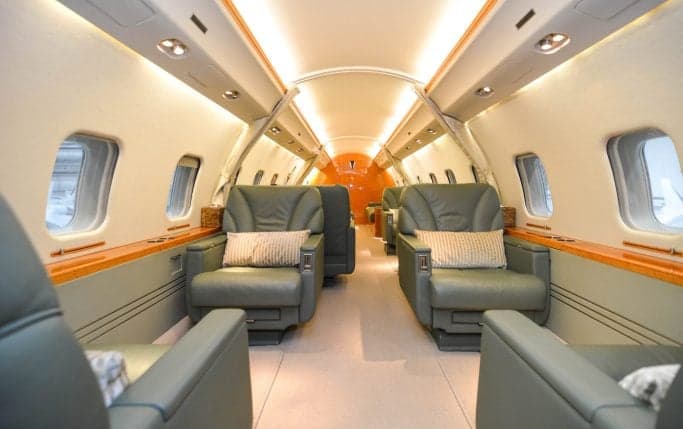 A white Bombardier Global Express aircraft parked inside a hangar.