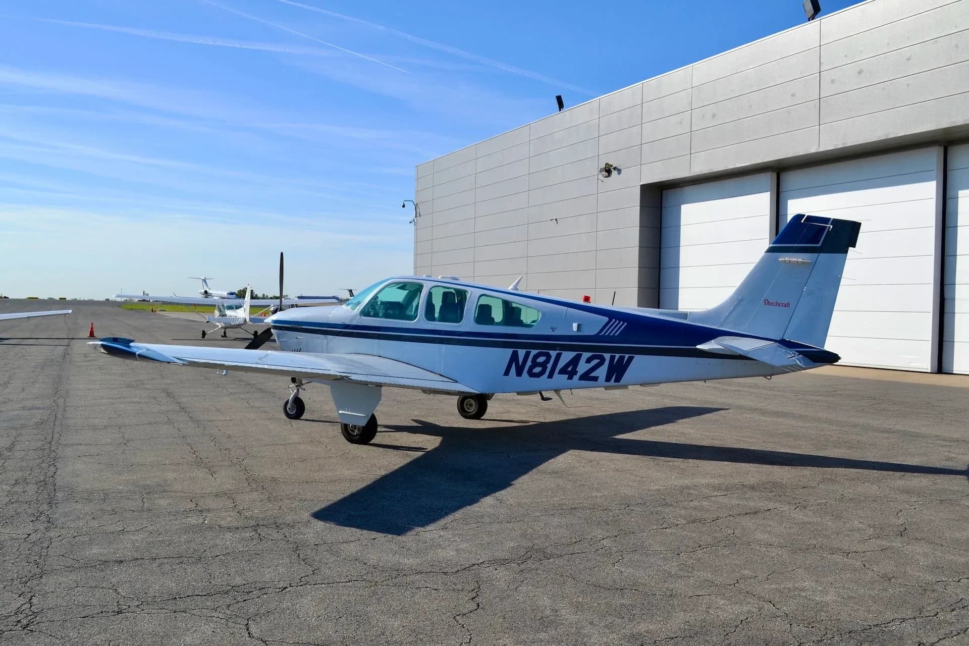 Beechcraft Bonanza N8142W parked on the tarmac with a blue and white paint scheme.