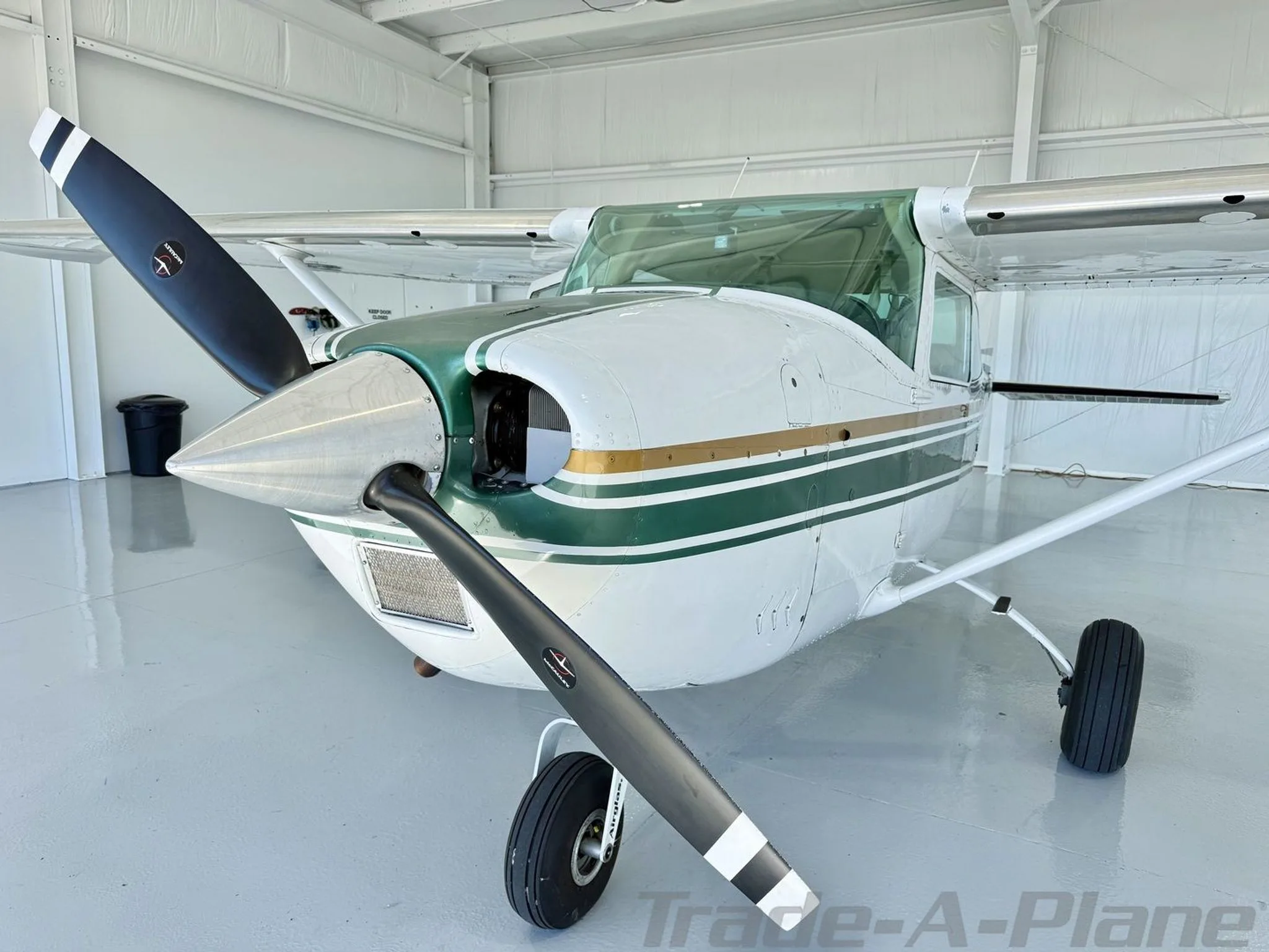 A close-up front view of the white and green Cessna Skylane N92099, showing the propeller and nose.