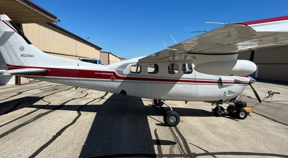 Side view of a red and white Cessna Centurion II aircraft, registration N528WA, parked on an airfield.