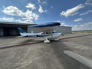 Cessna 172 Skyhawk, registration N759CB, parked on the tarmac in front of a hangar.