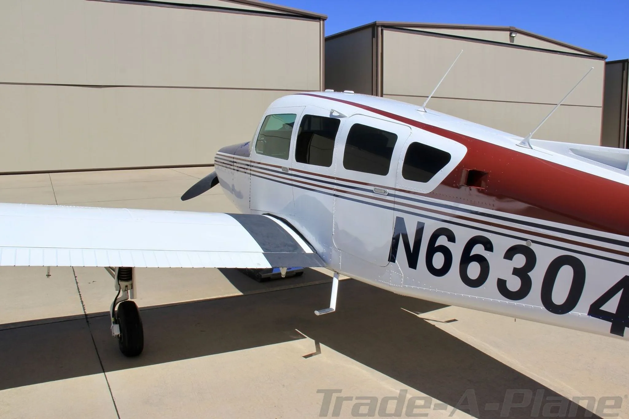 A close-up side view of the fuselage and wing of aircraft N66304, showing its white, red, and blue paint scheme.