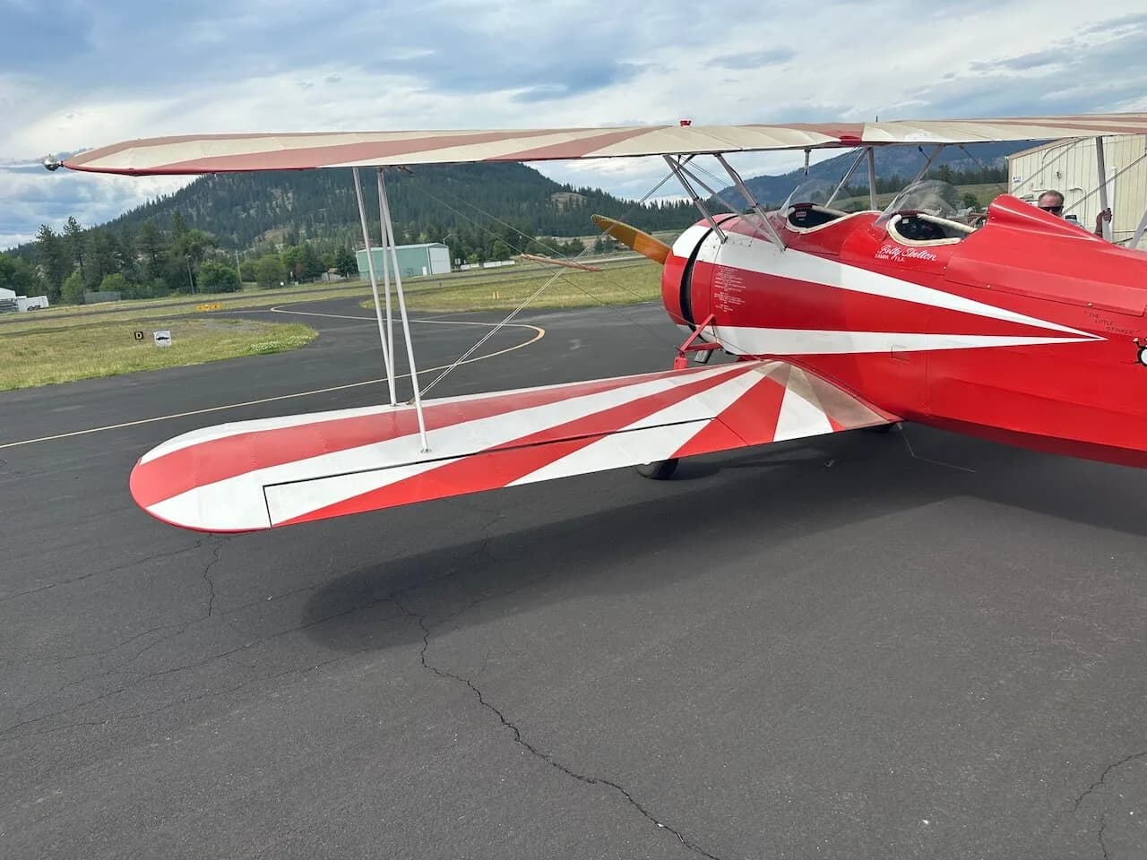A close-up side view of the red and white biplane, showing its lower wing and part of the fuselage.