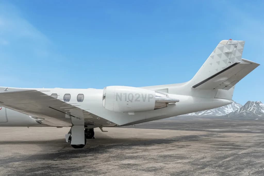 A close-up of the tail section of a white Cessna Citation CJ3 (N102VP) showing the engine and geometric tail pattern.