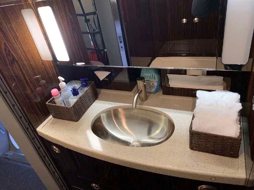 Bathroom sink and countertop inside the aircraft cabin with toiletries and a mirror.