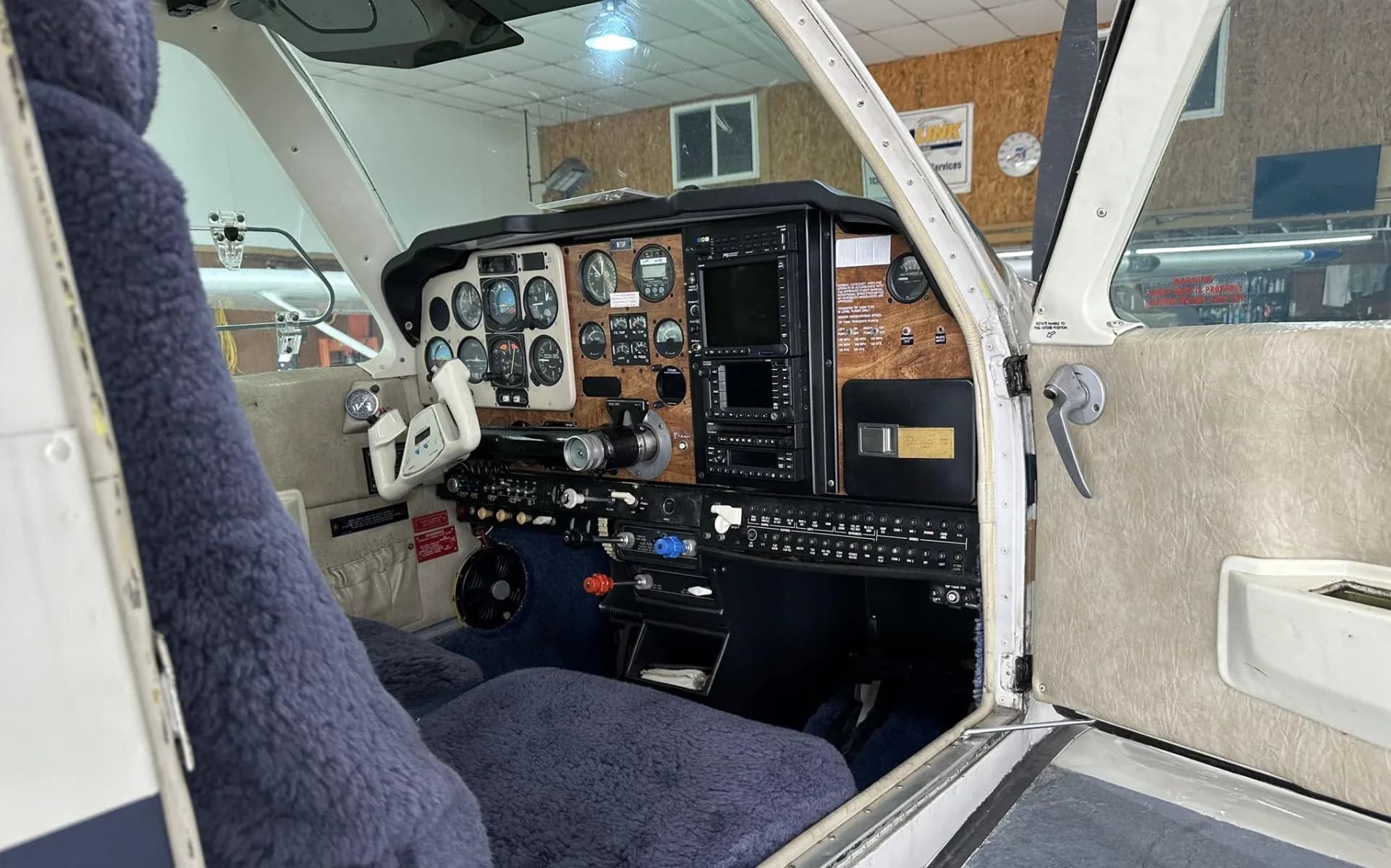 The cockpit of a Beechcraft Bonanza N7SP, showing the instrument panel and blue sheepskin seats.