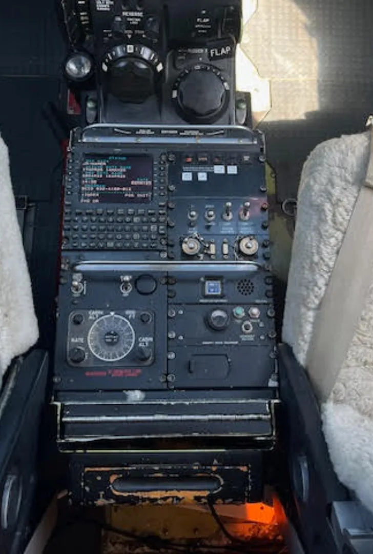 A close-up view of the center console in an aircraft cockpit, featuring various controls and a display screen.