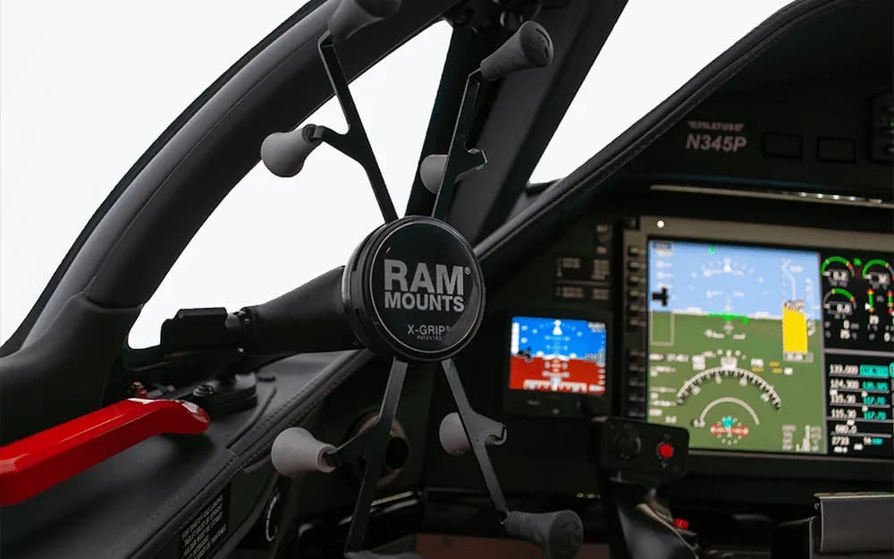 A close-up view of a RAM Mounts phone holder attached to the control yoke in the Pilatus PC-12 NGX cockpit.