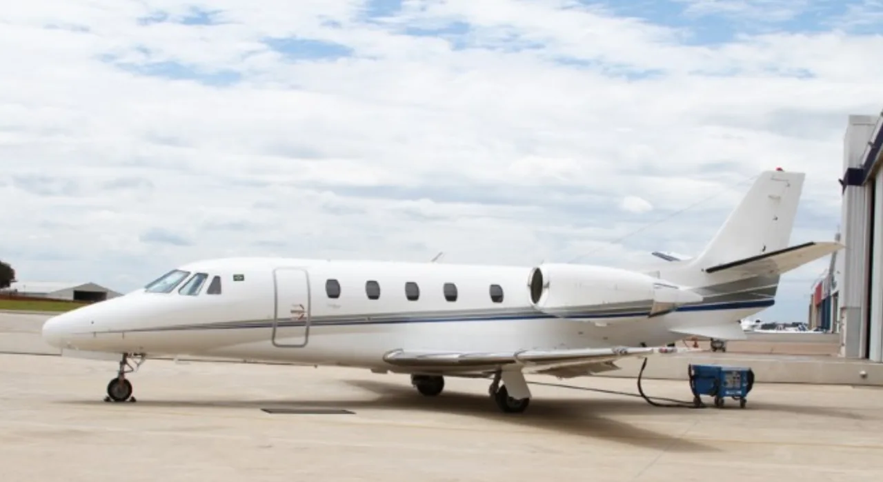 A white jet aircraft is parked on the tarmac with a blue and silver stripe.