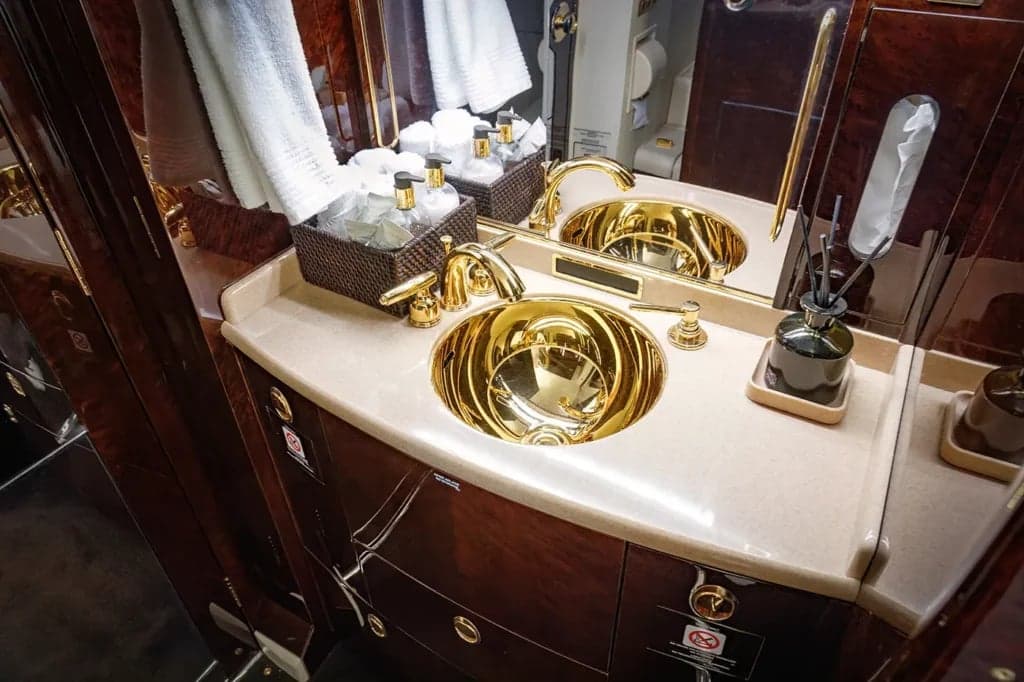 A gold sink and vanity in the aircraft lavatory.
